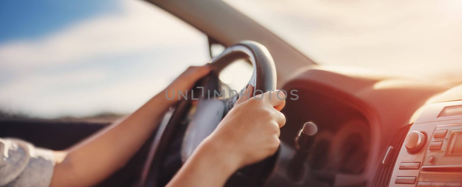 Woman's hands holding steering wheel inside car. Concept of freedom and road trip.