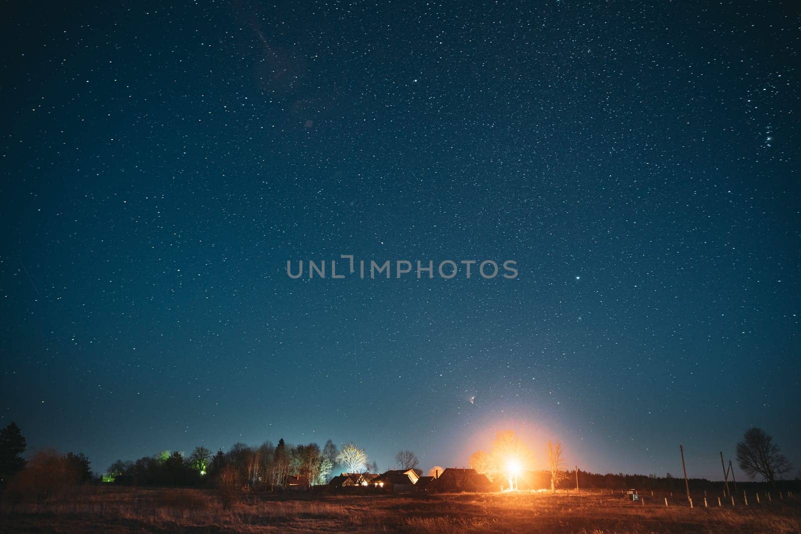 Real Night Sky Stars Above Old Village. Natural Starry Sky Above Rural Countryside Landscape In Belarus.