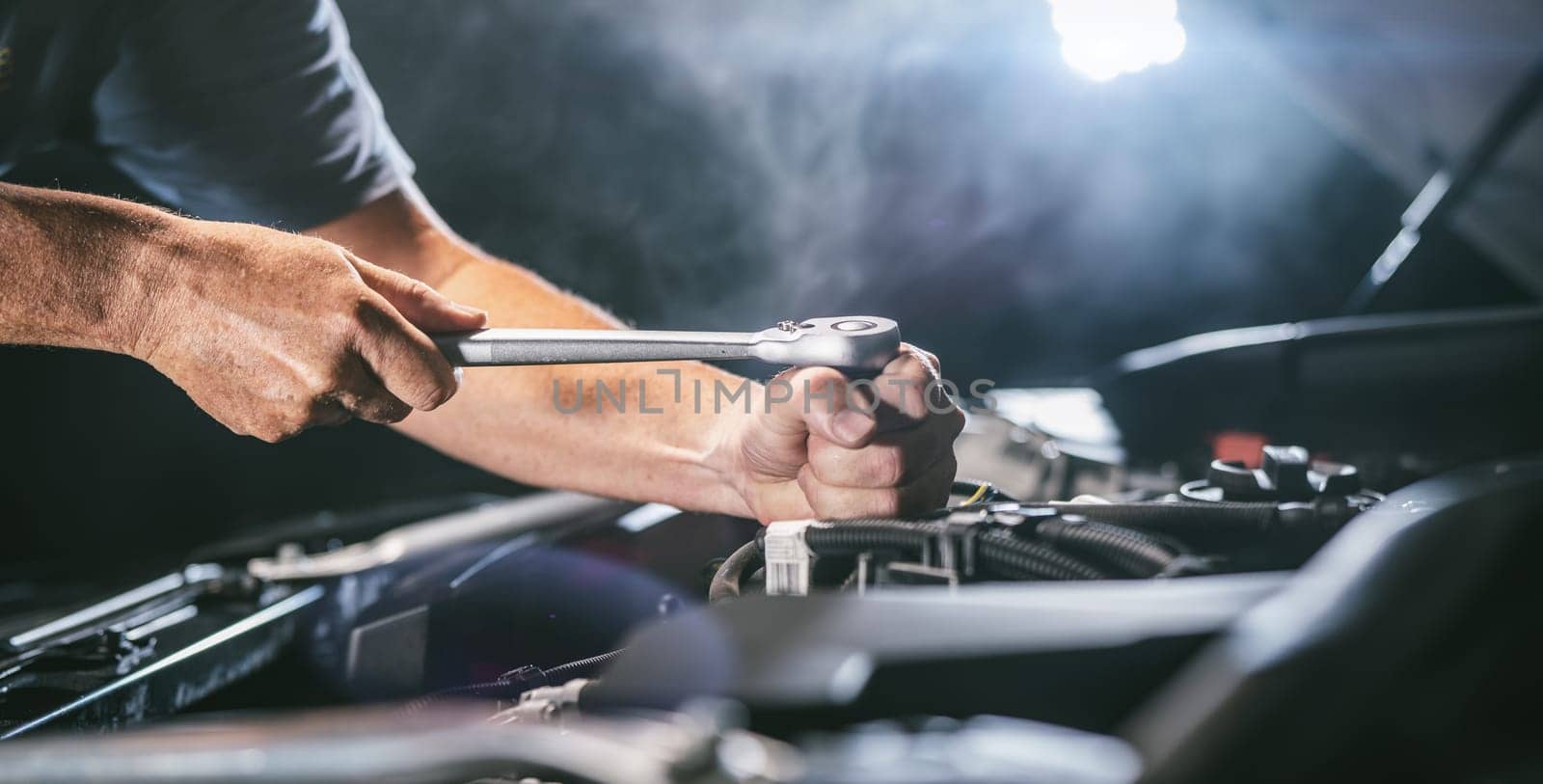Auto mechanic working on car engine in mechanics garage. Repair service. authentic close-up shot - selective focus with motion blur
