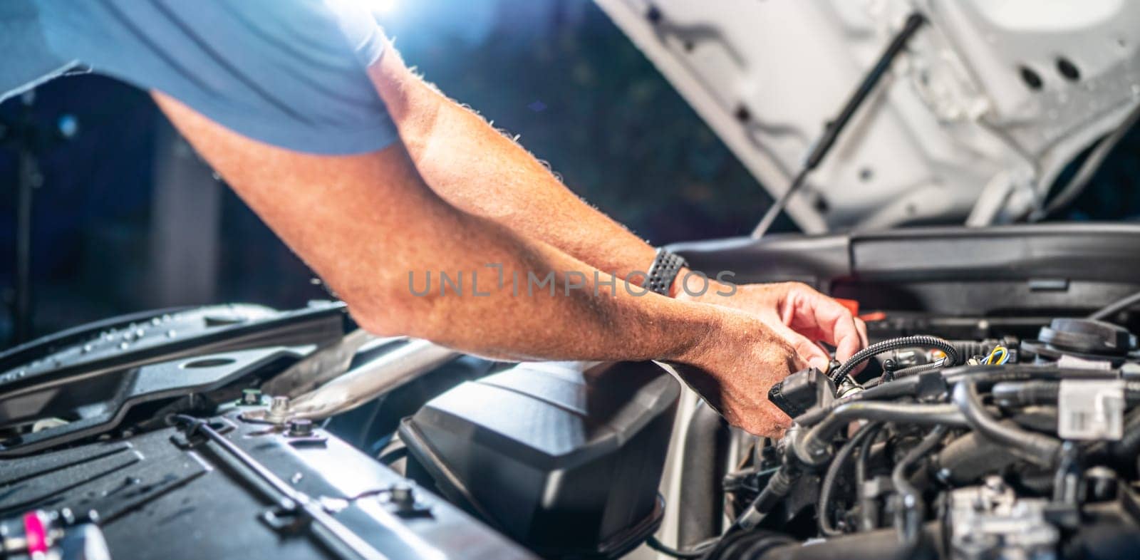 Auto mechanic working on car engine in mechanics garage. Repair service. authentic close-up shot - selective focus with motion blur