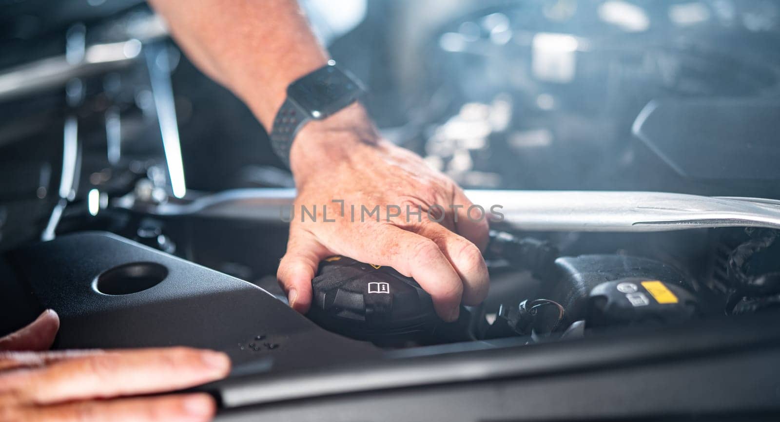 Auto mechanic working on car engine in mechanics garage. Repair service. authentic close-up shot - selective focus with motion blur