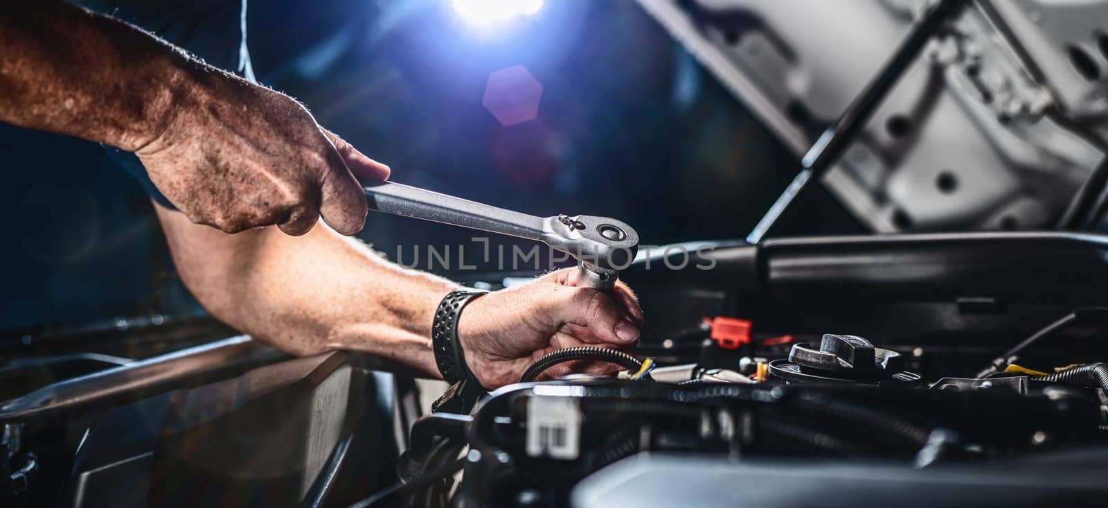 Auto mechanic working on car engine in mechanics garage. Repair service. authentic close-up shot - selective focus with motion blur