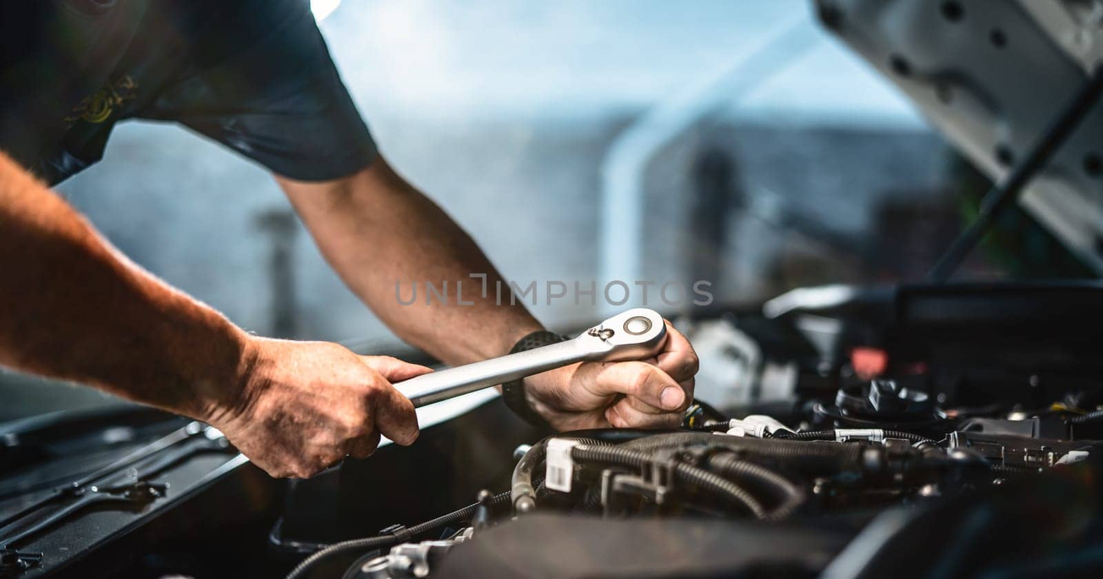 Auto mechanic working on car engine in mechanics garage. Repair service. authentic close-up shot - selective focus with motion blur
