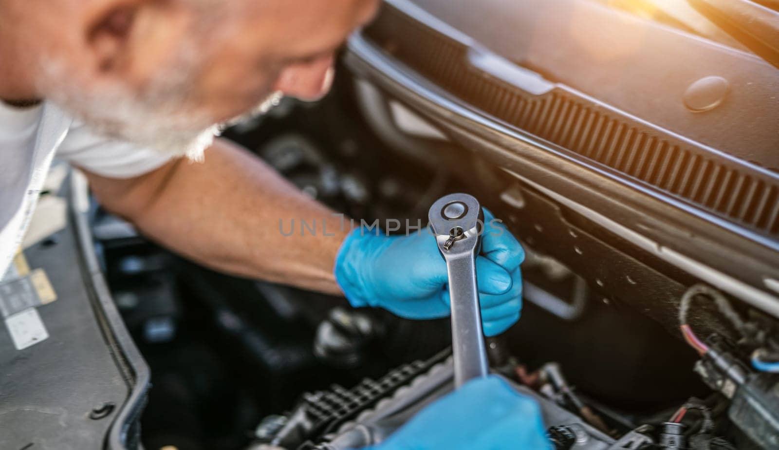 Auto mechanic working on car engine in mechanics garage. Repair service. authentic close-up shot