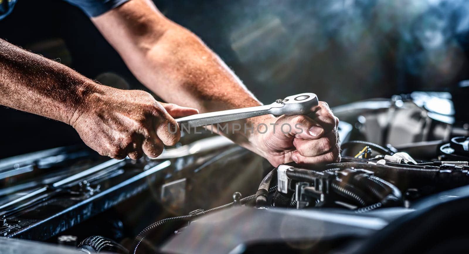 Auto mechanic working on car engine in mechanics garage. Repair service. authentic close-up shot - selective focus with motion blur