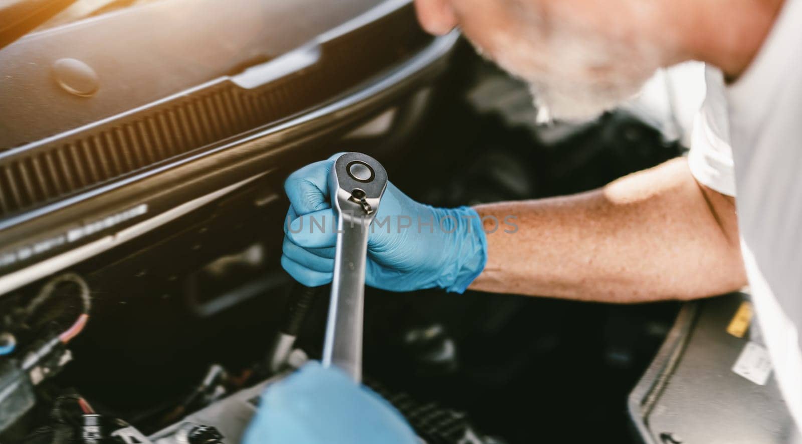 Auto mechanic working on car engine in mechanics garage. Repair service. authentic close-up shot - selective focus