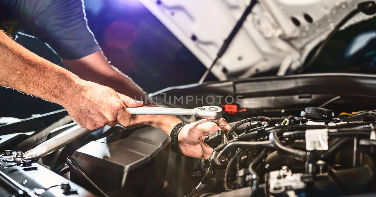 Auto mechanic working on car engine in mechanics garage. Repair service. authentic close-up shot - selective focus with motion blur