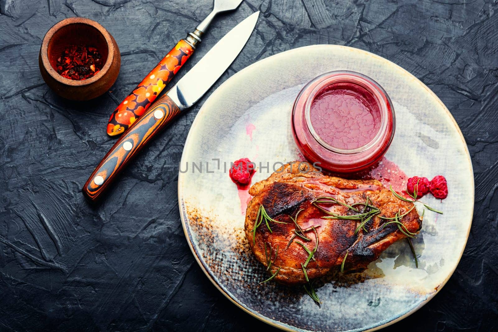 Roasted pork steak on a plate and raspberry sauce