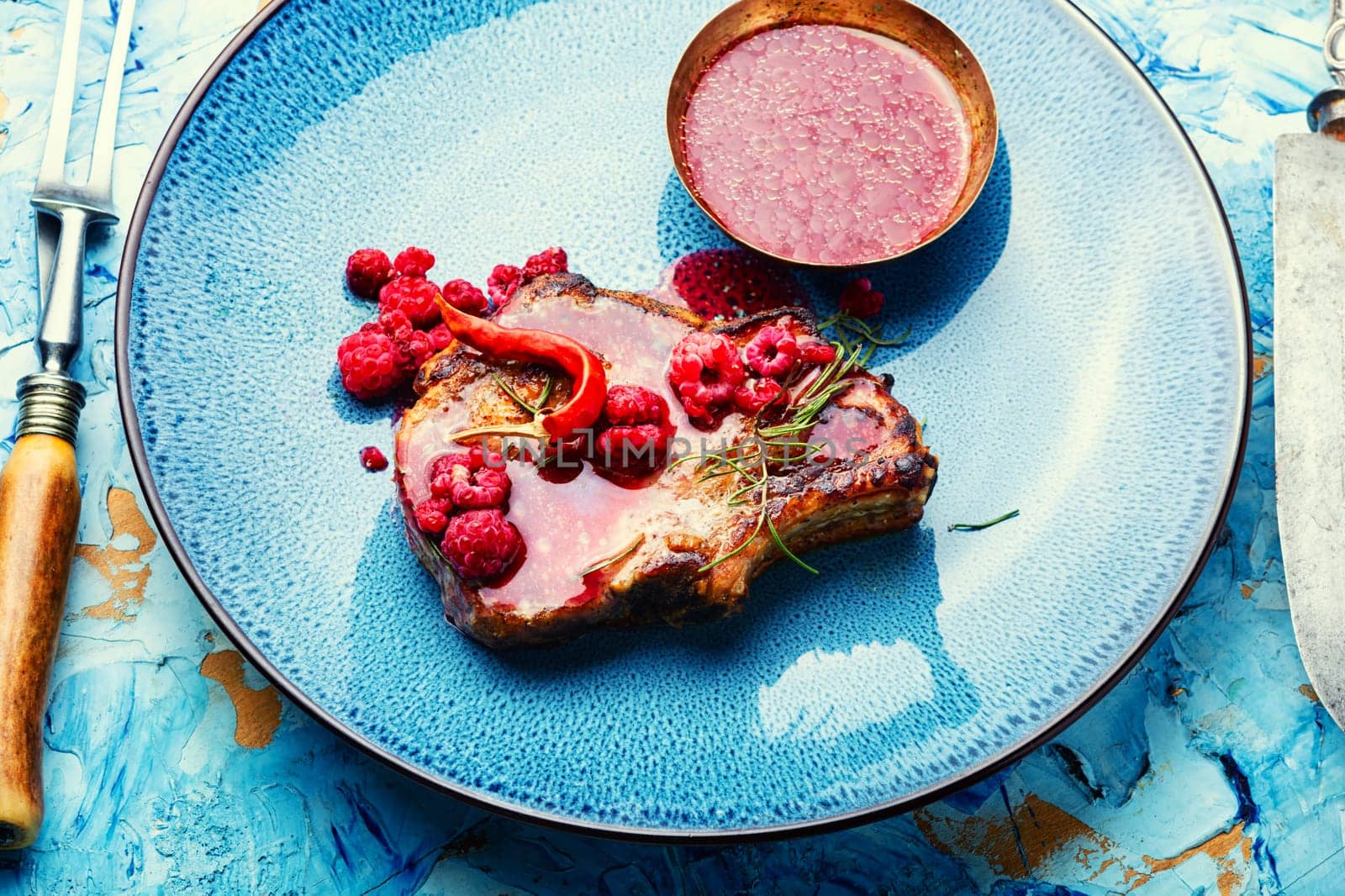 Roasted pork steak on a plate and raspberry sauce