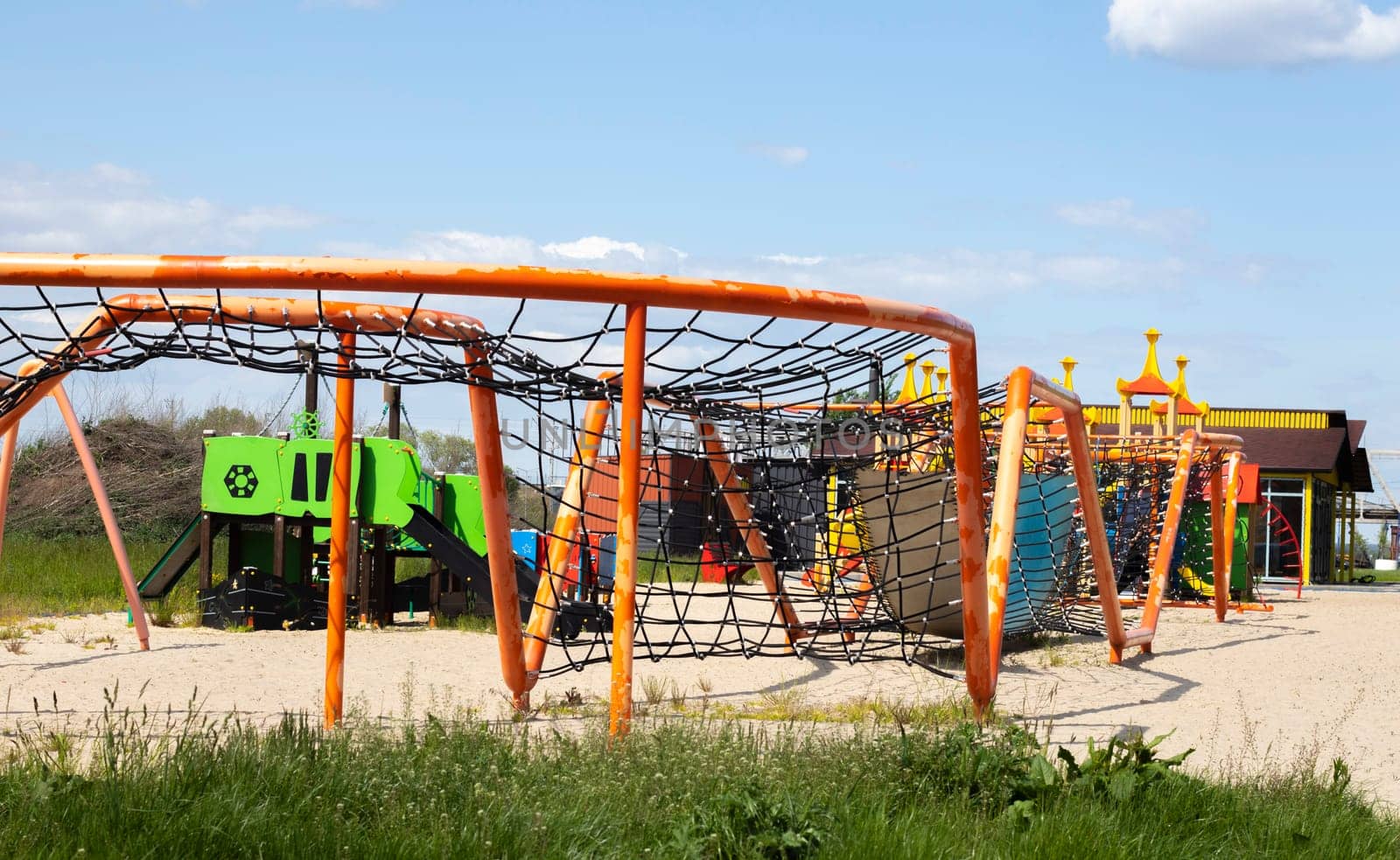 Modern public playground against the blue sky. A colorful play and sports complex for children without people. Equipment for rock climbing and assault on the playground