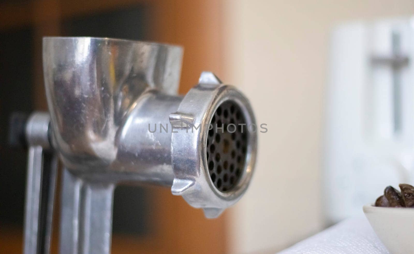 The classic manual iron meat grinder is fixed on the table. Antique, vintage meat grinder in the kitchen, close-up. The meat grinder is ready to go