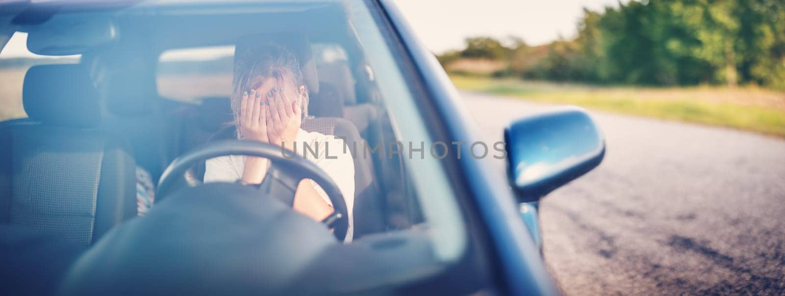 Upset woman sitting in the car and covering face with her hands. Concept of a accident and traffic violations.