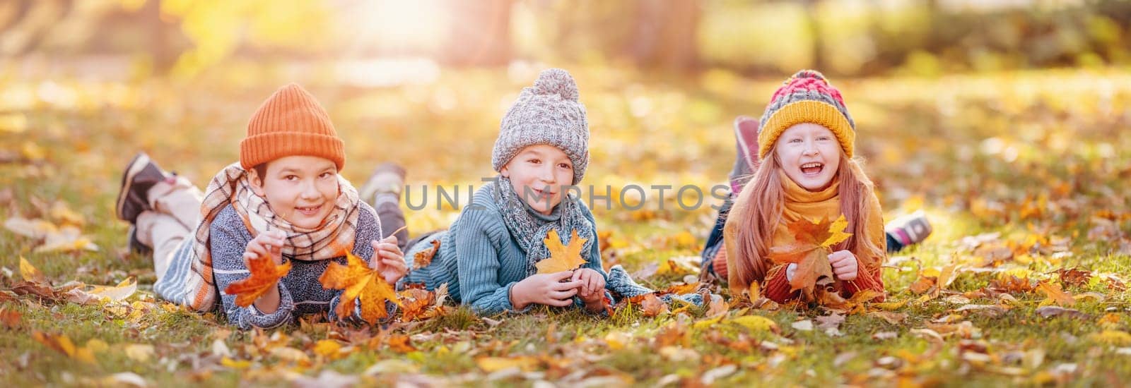 Group of children lying onthe ground in autumnal park. Concept of friendship and family vacation.