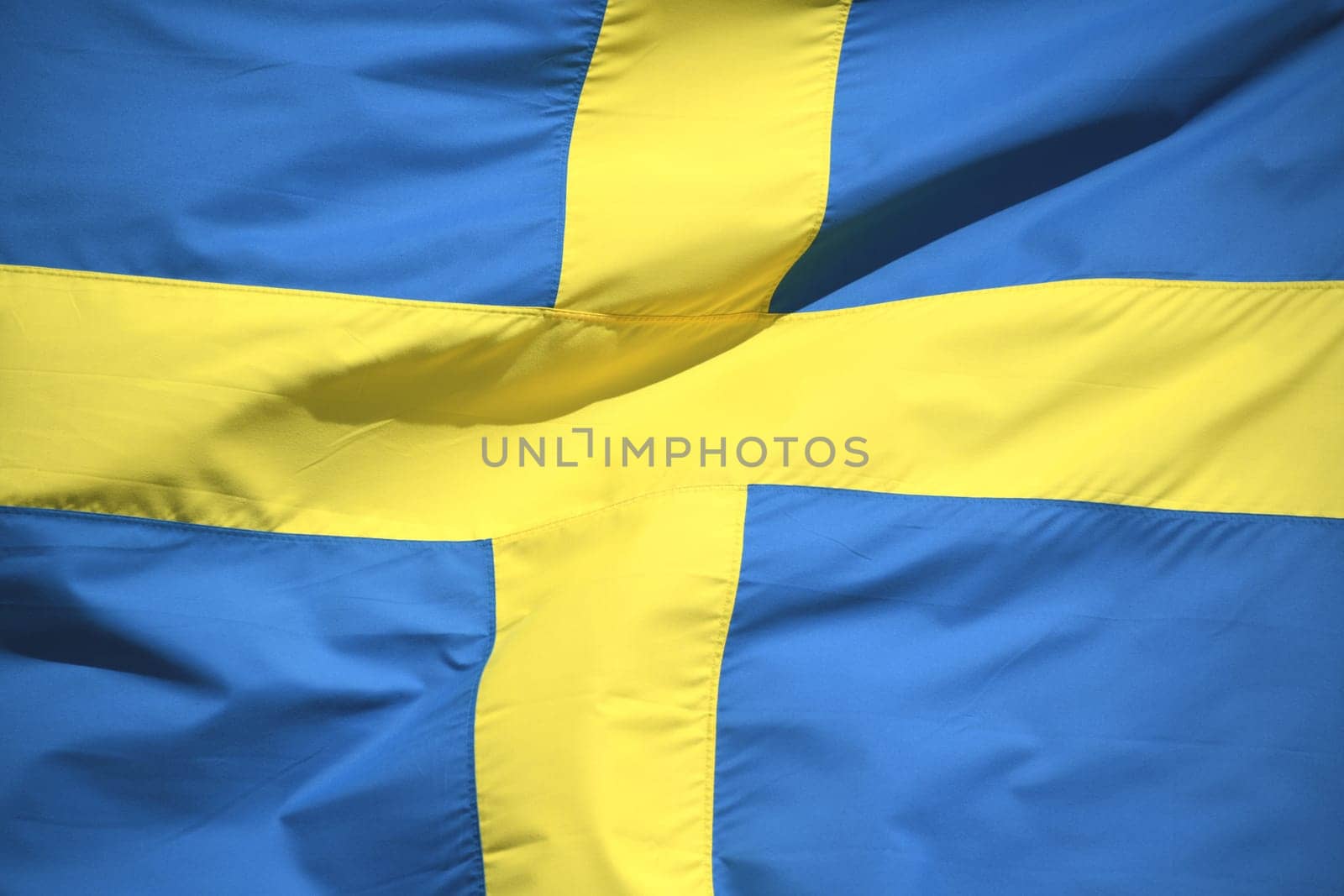 The national flag of Sweden in the colors blue and yellow is waving in the wind. The krone is the currency of Sweden.