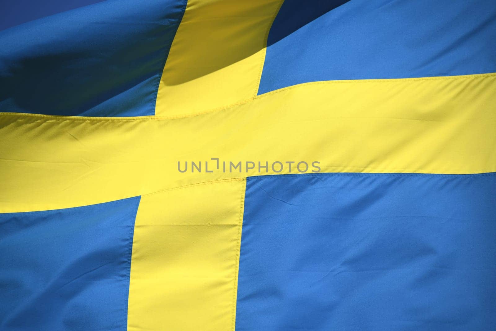 The national flag of Sweden in the colors blue and yellow is waving in the wind. The krone is the currency of Sweden.