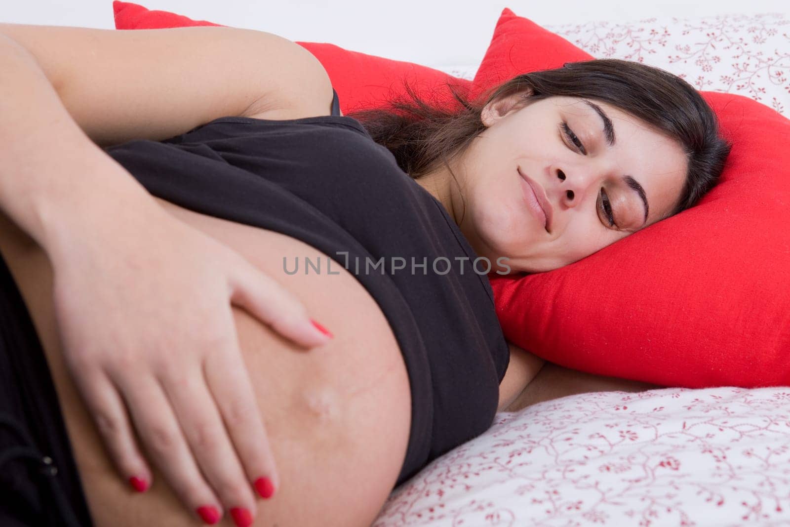 young pregnant woman in bed, focus on the belly
