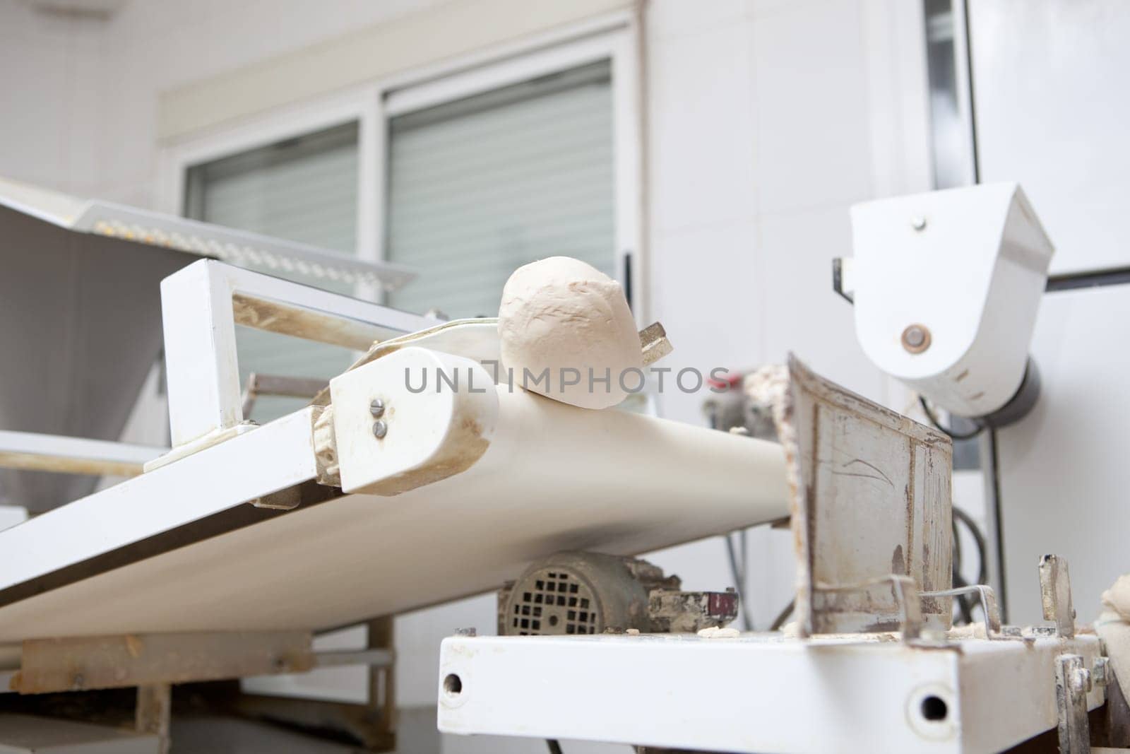 Dough divider and moulder machine at work. Manufacturing process of spanish bread