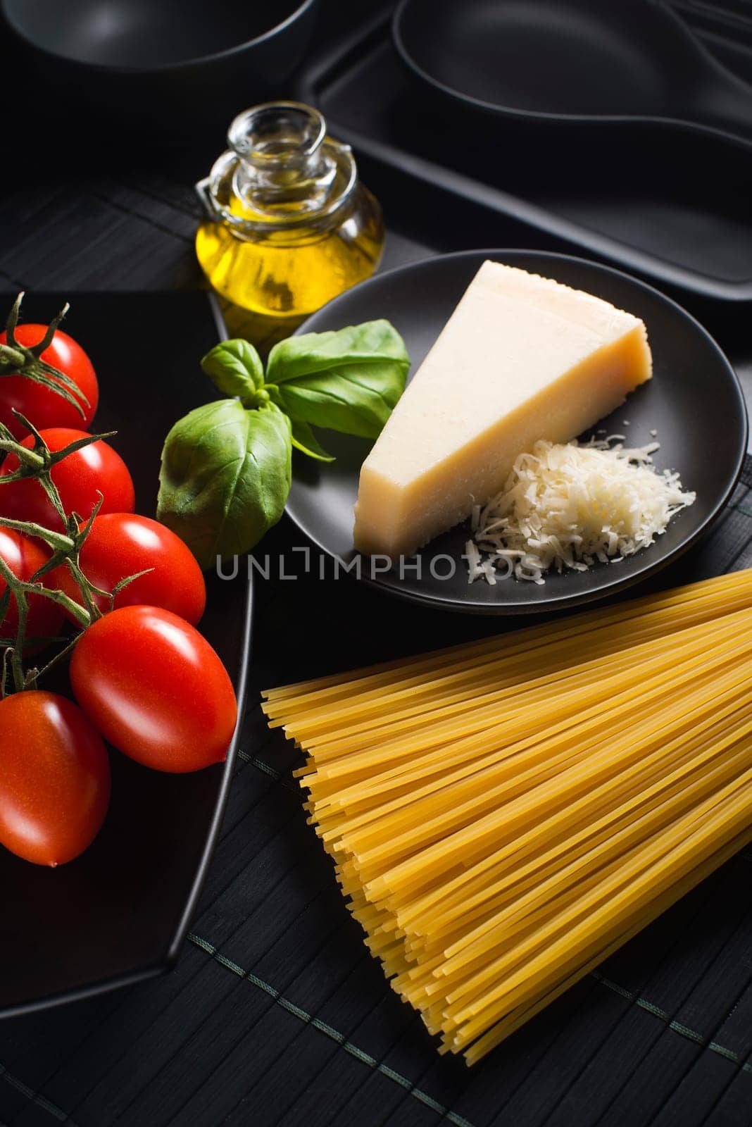 Spaghetti and tomatoes with parmesan cheese on black table
