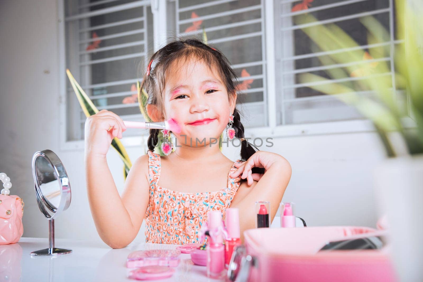 Happy kid is beautiful make up with cosmetics toy, Asian adorable funny little girl making makeup her face she looking in the mirror and cheek fluffy brush for powder, Learning activity to be woman