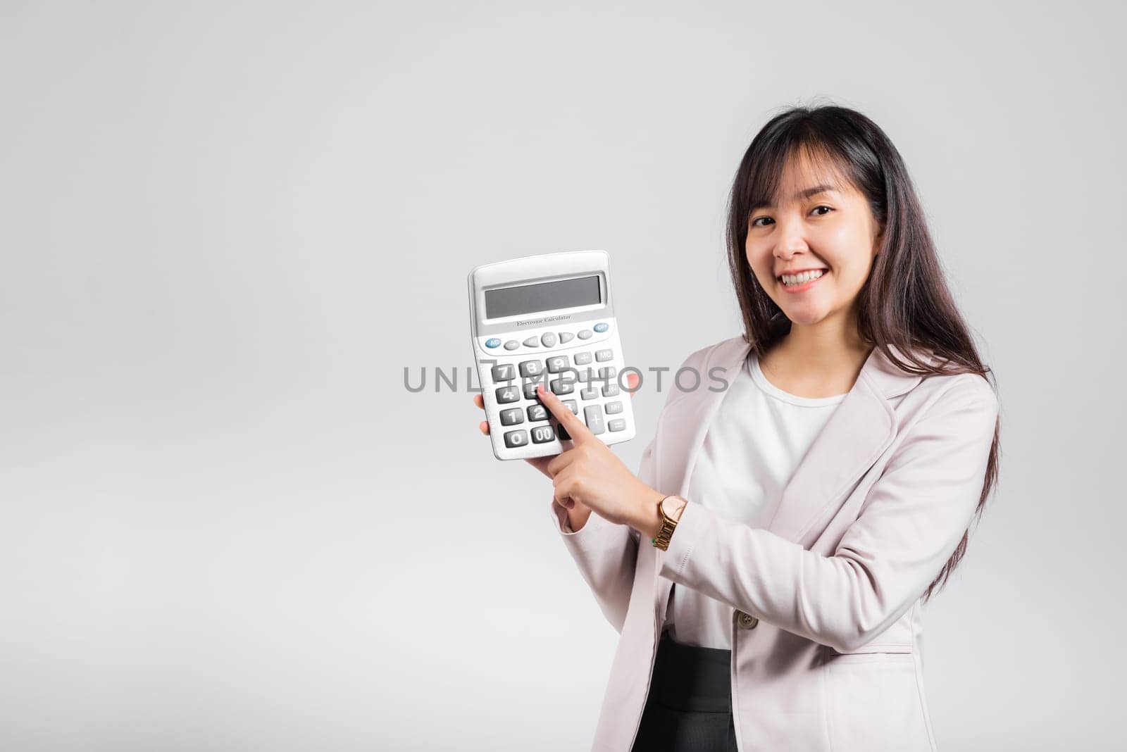 Tax day concept. Woman confident smiling holding calculator and finger point device, Portrait excited happy Asian female studio shot isolated on white background, Account and finance counting income