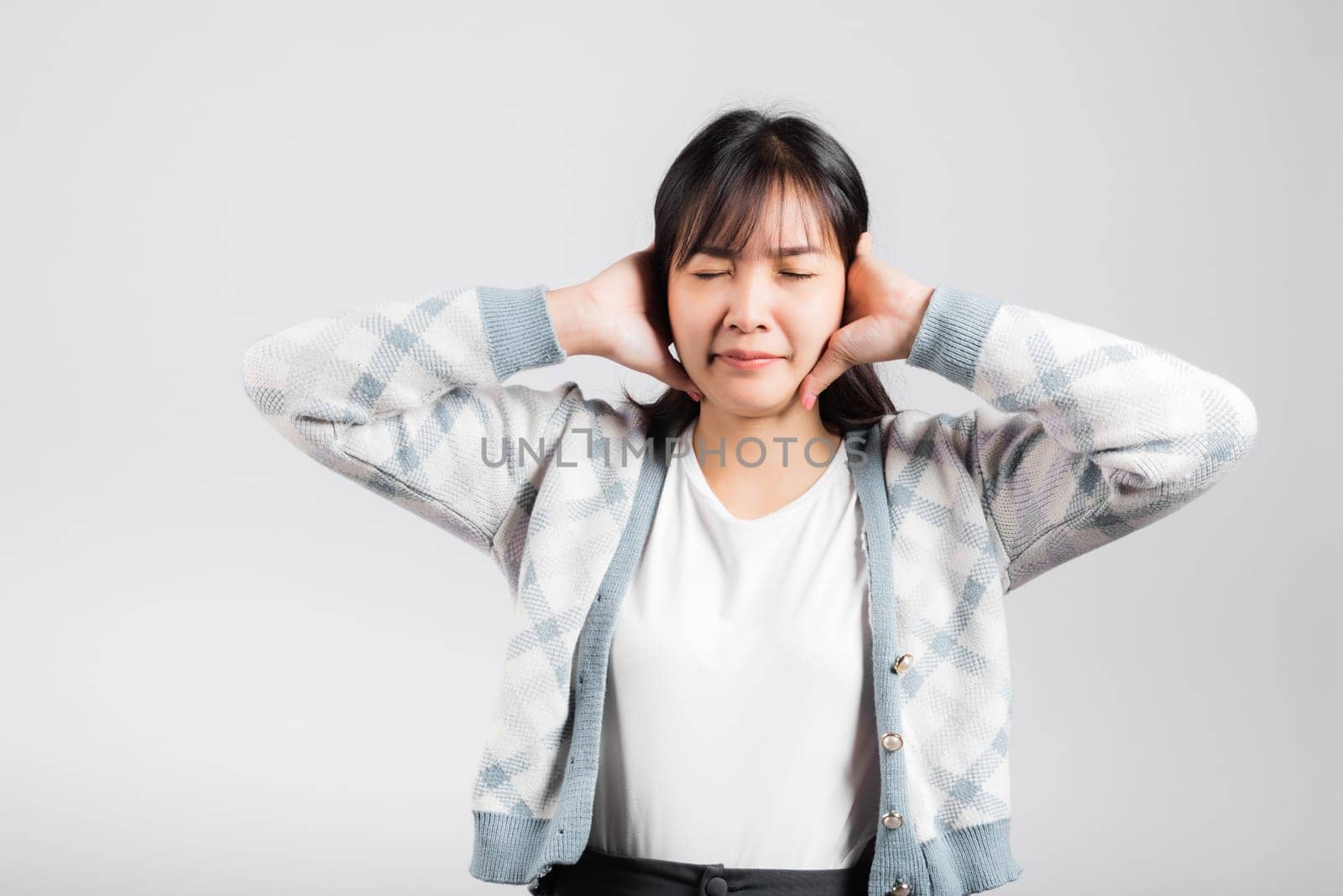 Woman bad mood pain her closed ears with hand palms and close eyes, Asian beautiful young female covers ears for loud noise, studio shot isolated on white background with copy space