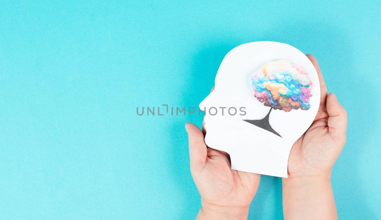 Holding a head with a colorful tree in the hands, symbol for creativity, connection to nature and positive emotion, living in a dream world