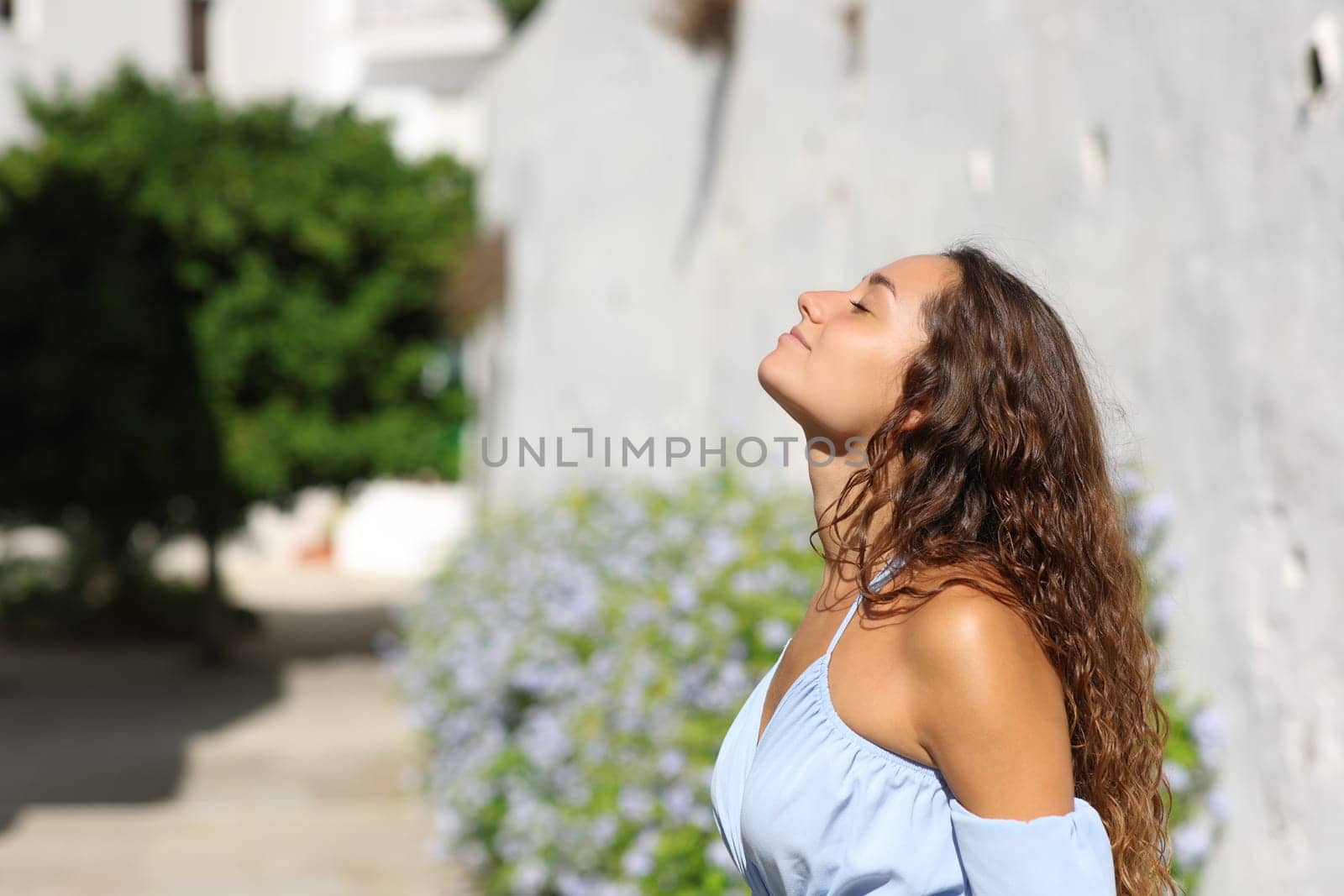 Side view portrait of a woman breathing fresh air in a white town street