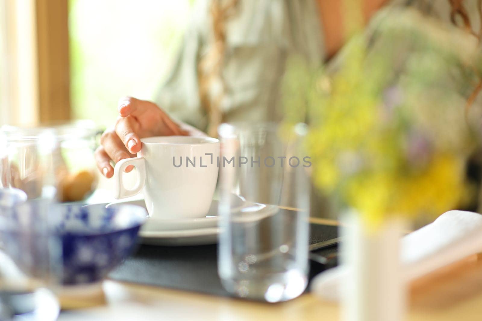 Close up of a woman hand holding a coffee mug in a restaurant