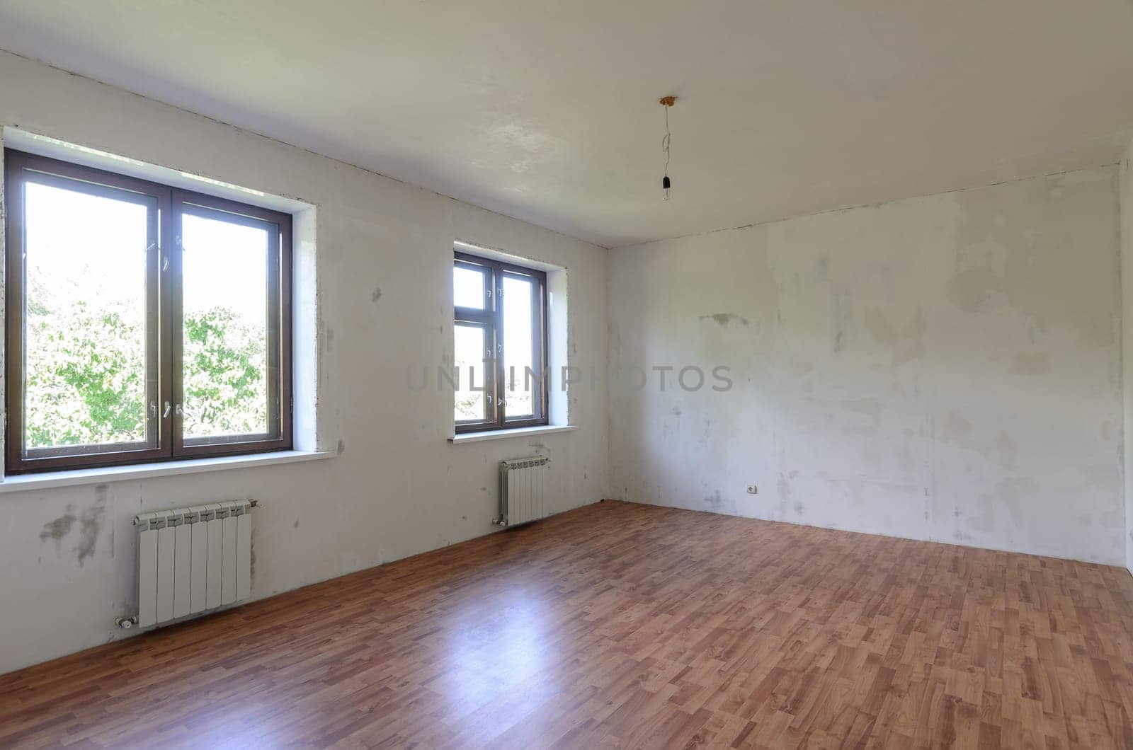Interior of an empty room during renovation, there are two large windows in the room