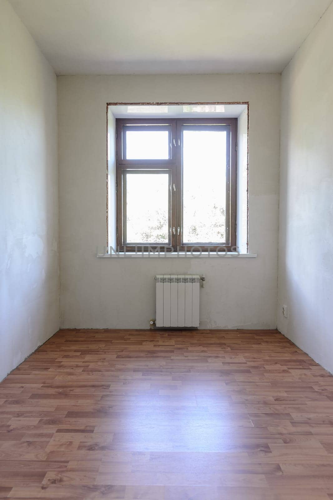 View of the window in a small room after renovation, wood-effect laminate is laid on the floor