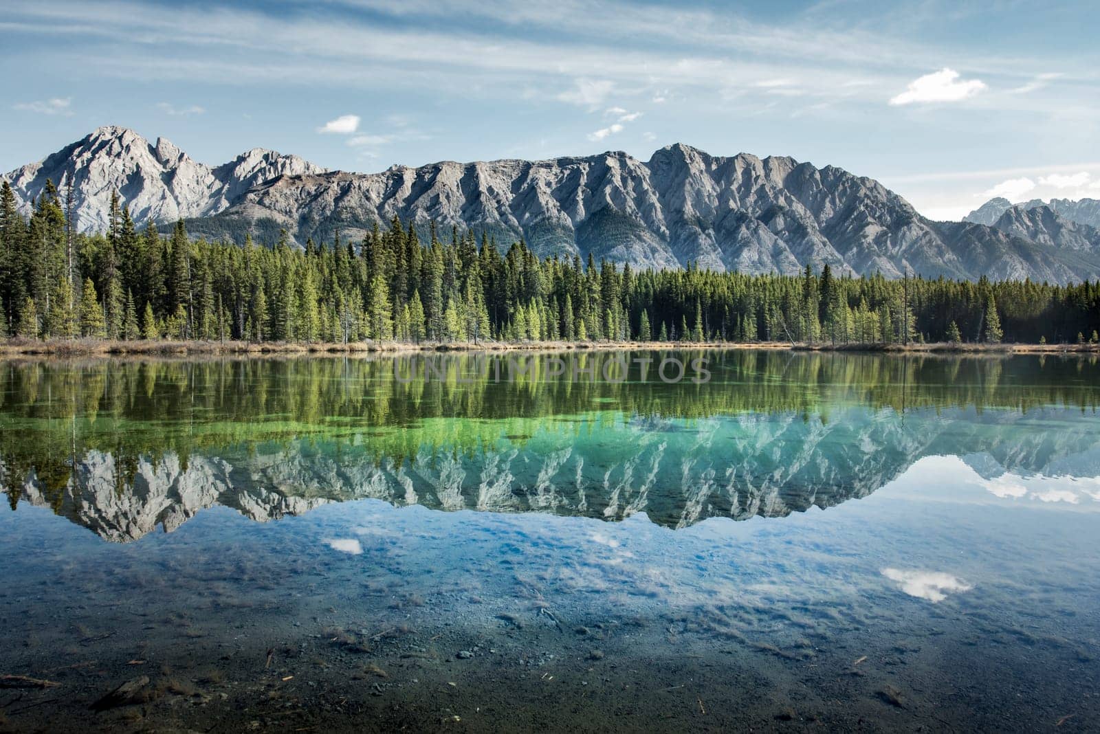 Sky and peaks are reflected in a crystal clear mountain lake