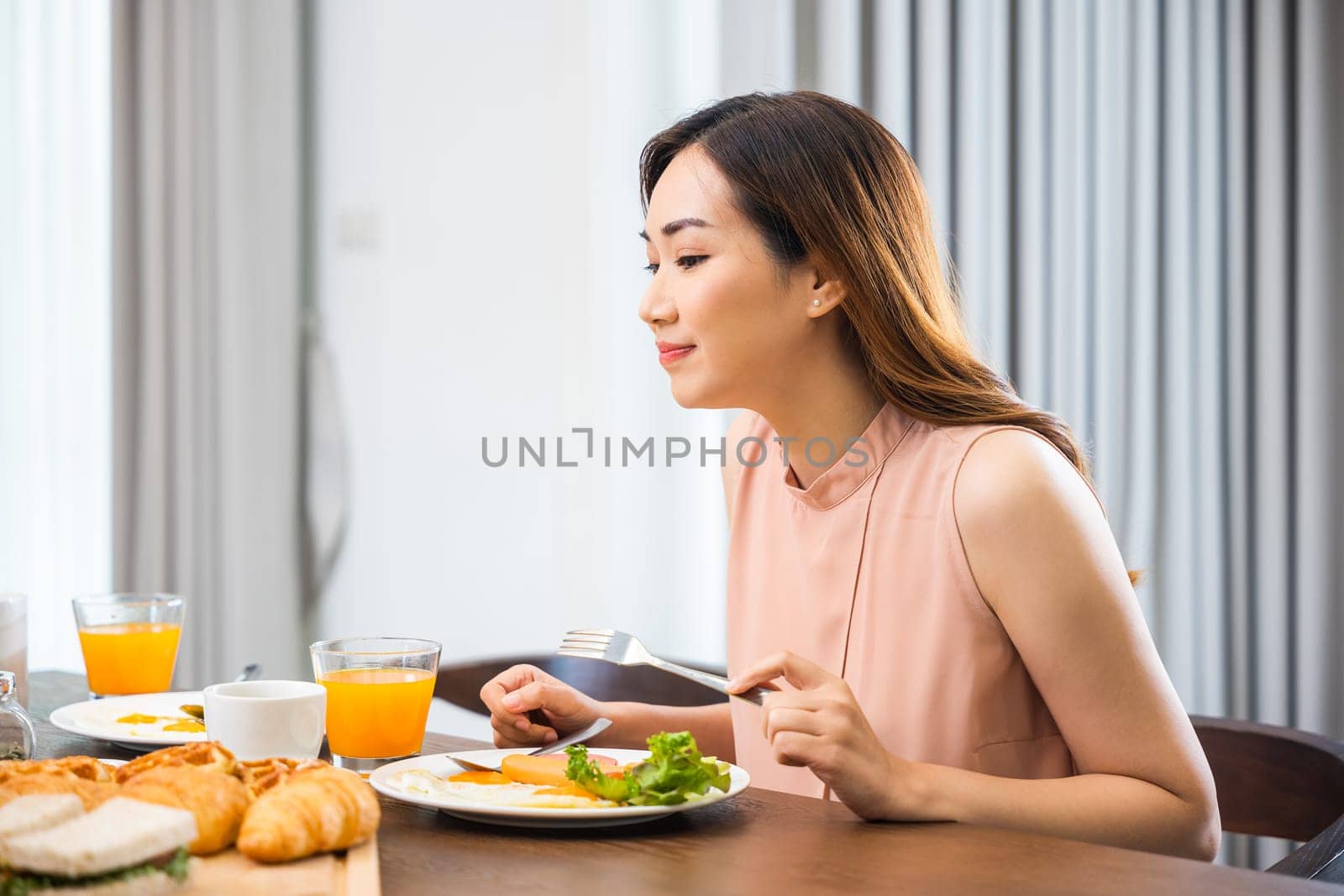 Woman eat fresh breakfast served food with beverage before go to work in the morning at home, Asian young female sitting kitchen table food having eating healthy breakfast at home