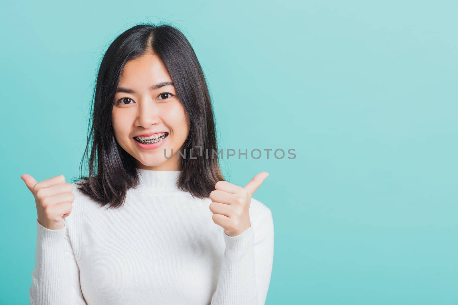 Young beautiful Asian woman cheerful smiling showing finger thumb up, Portrait happy female using showing like the gesture for good sign, studio shot isolated on a blue background