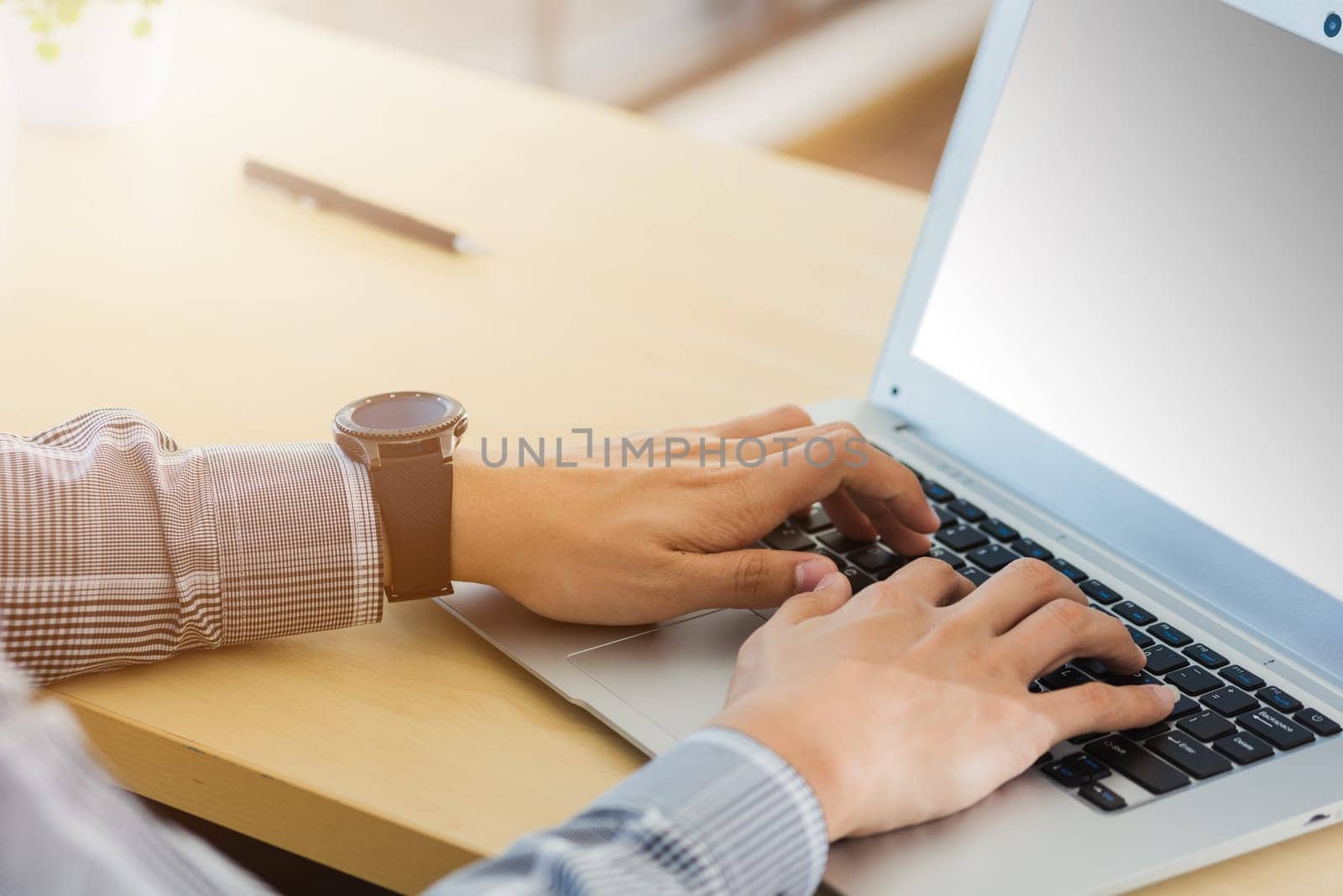 Asian businessman working on his laptop computer with blank copy space screen he typing on keyboard at home office desk. The man play social media on computer table