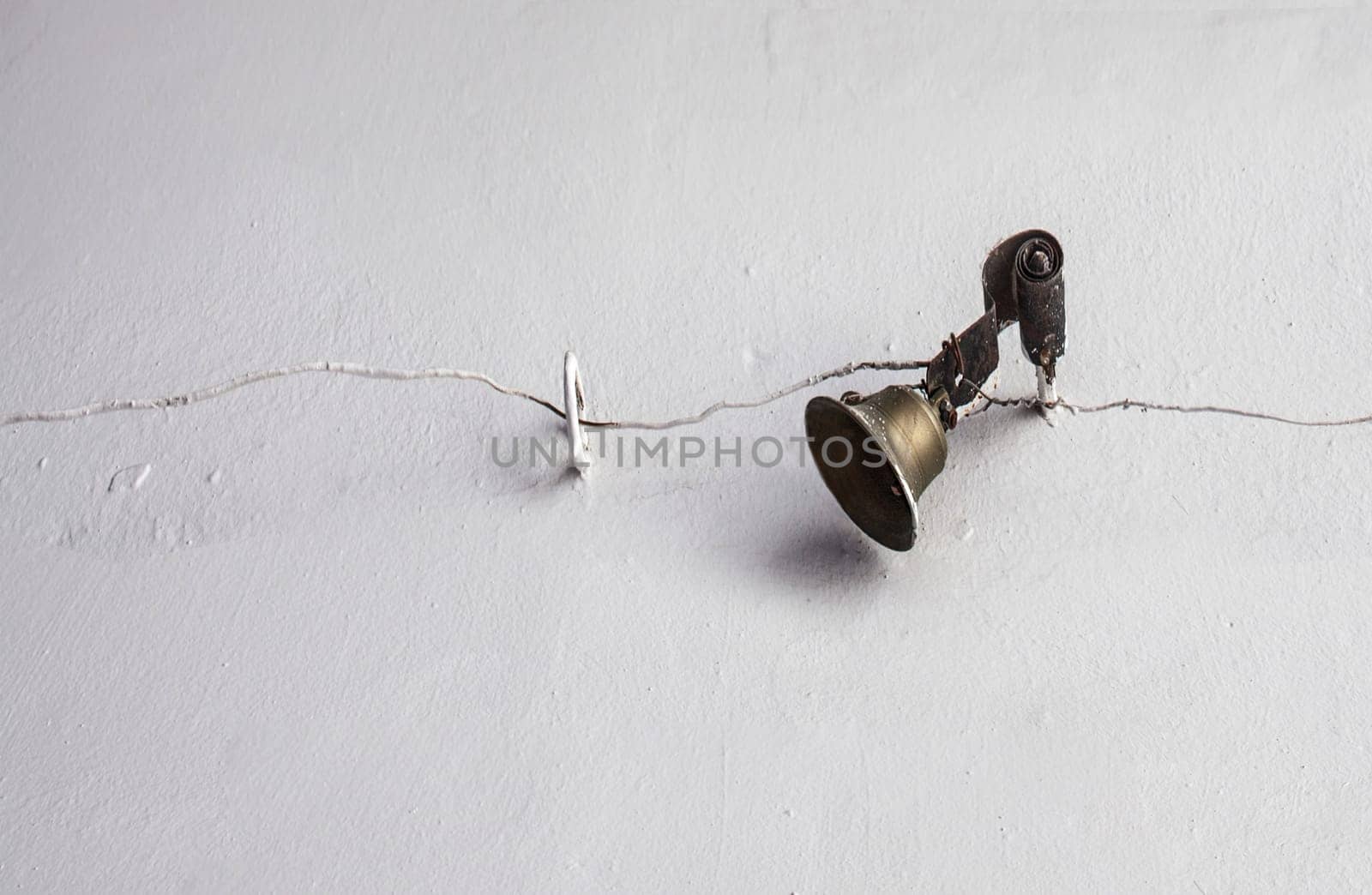 Mechanically operated doorbell on a torsion spring actuated by a wire. Bell nailed to whitewashed wall