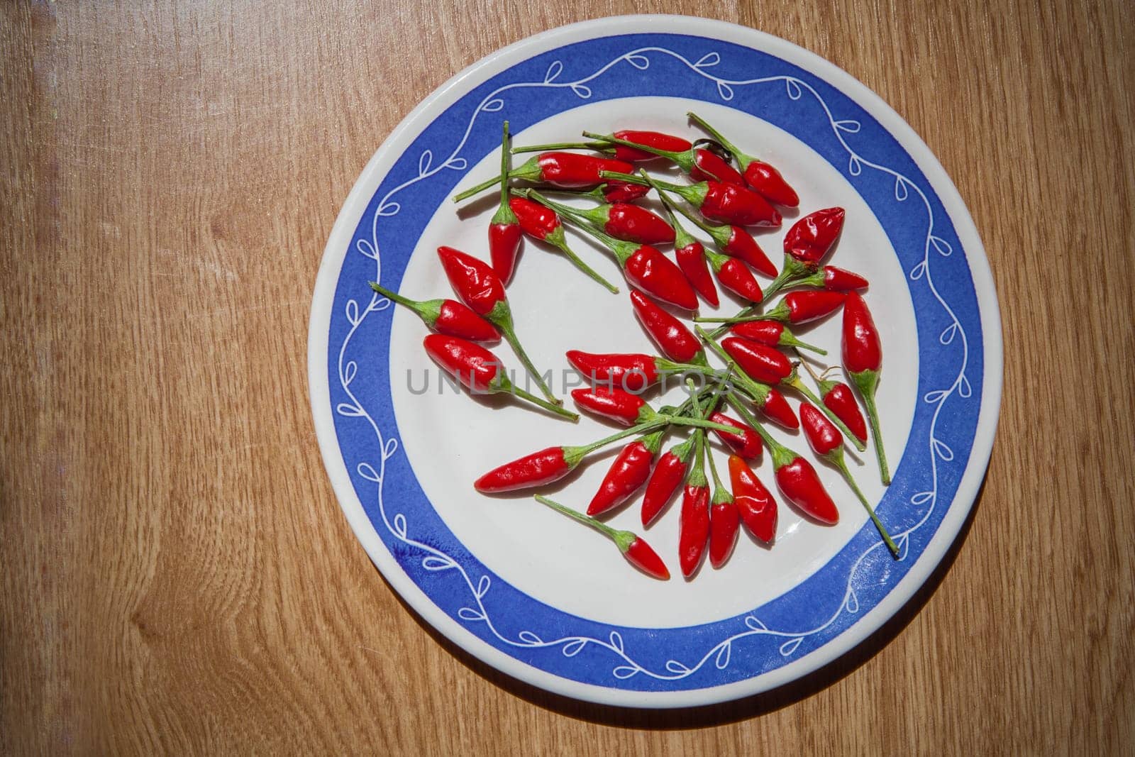 Plate with piri-piri chili pepper. Studio shot with natural light. Wooden background