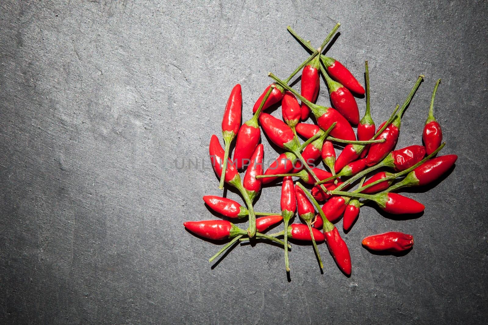 Black slate with piri-piri chili pepper. Studio shot with natural light. Wooden background