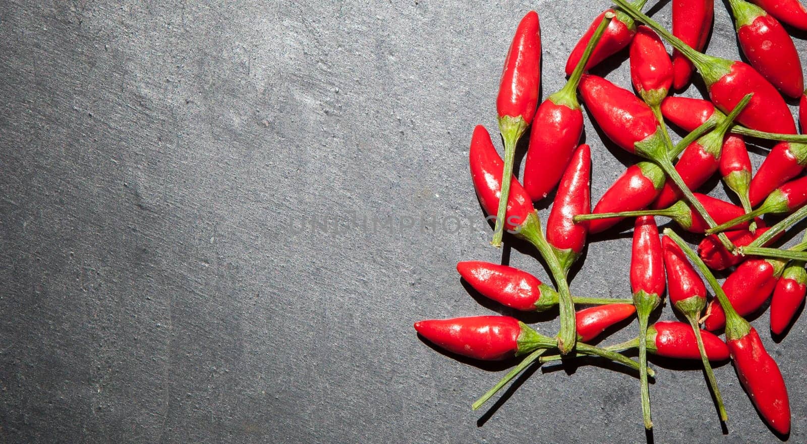 Black slate with piri-piri chili pepper. Studio shot with natural light. Wooden background