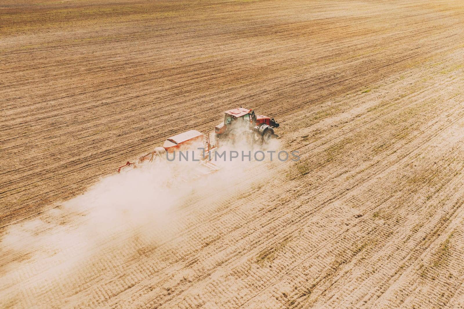Aerial View. Tractor With Seed Drill Machine Sowing The Seeds For Crops In Spring Season. Beginning Of Agricultural Spring Season. Countryside Rural Field Landscape.