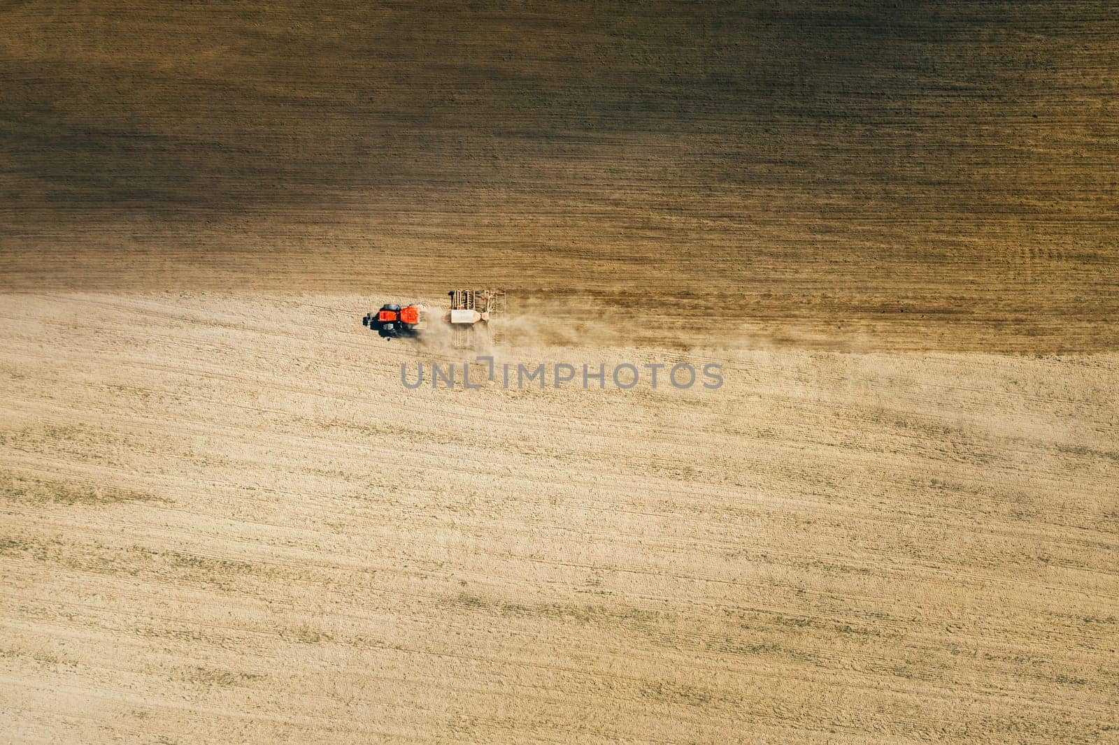 Aerial View. Tractor With Seed Drill Machine Sowing The Seeds For Crops In Spring Season. Beginning Of Agricultural Spring Season. Countryside Field Landscape. Natural Rural Background.