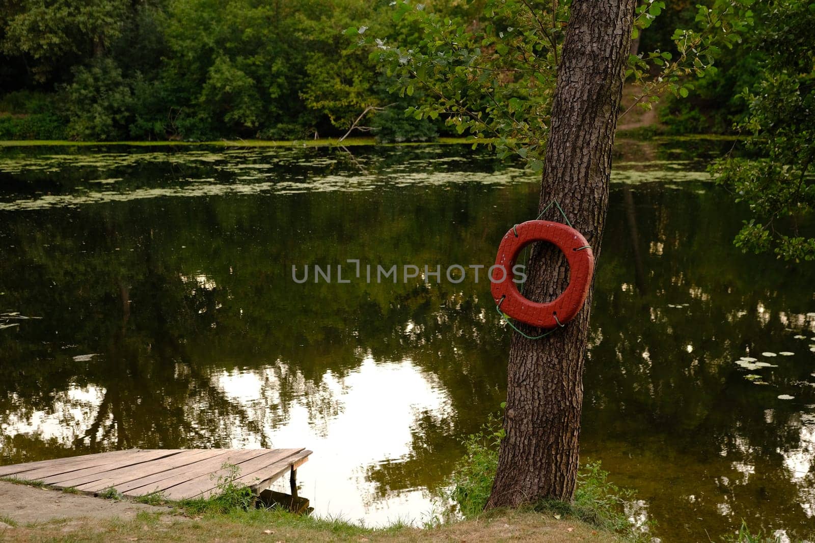 Lifebuoy ring on berth of the river with wooden pier outdoors.