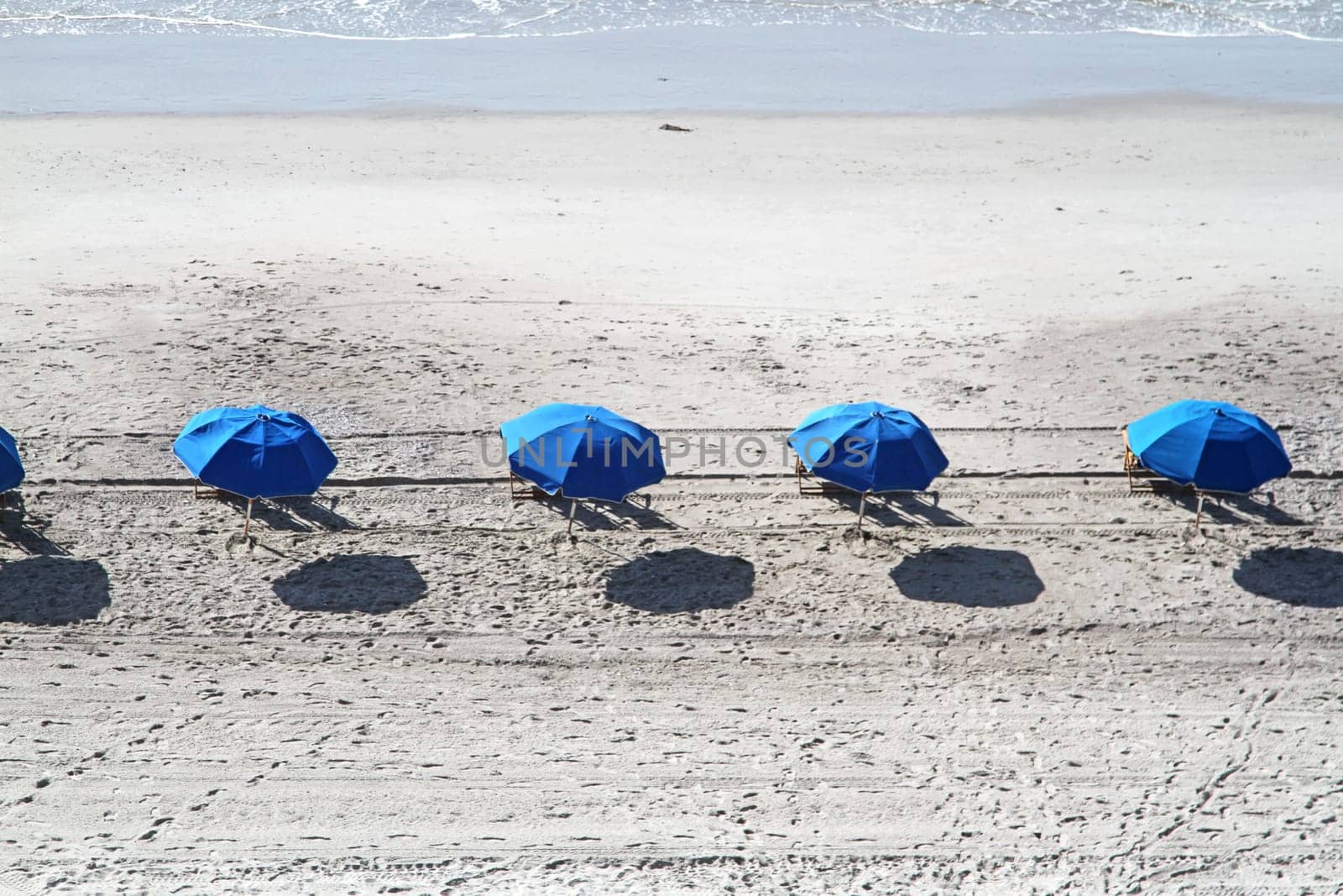 Beach umbrellas in a row on sandy beach