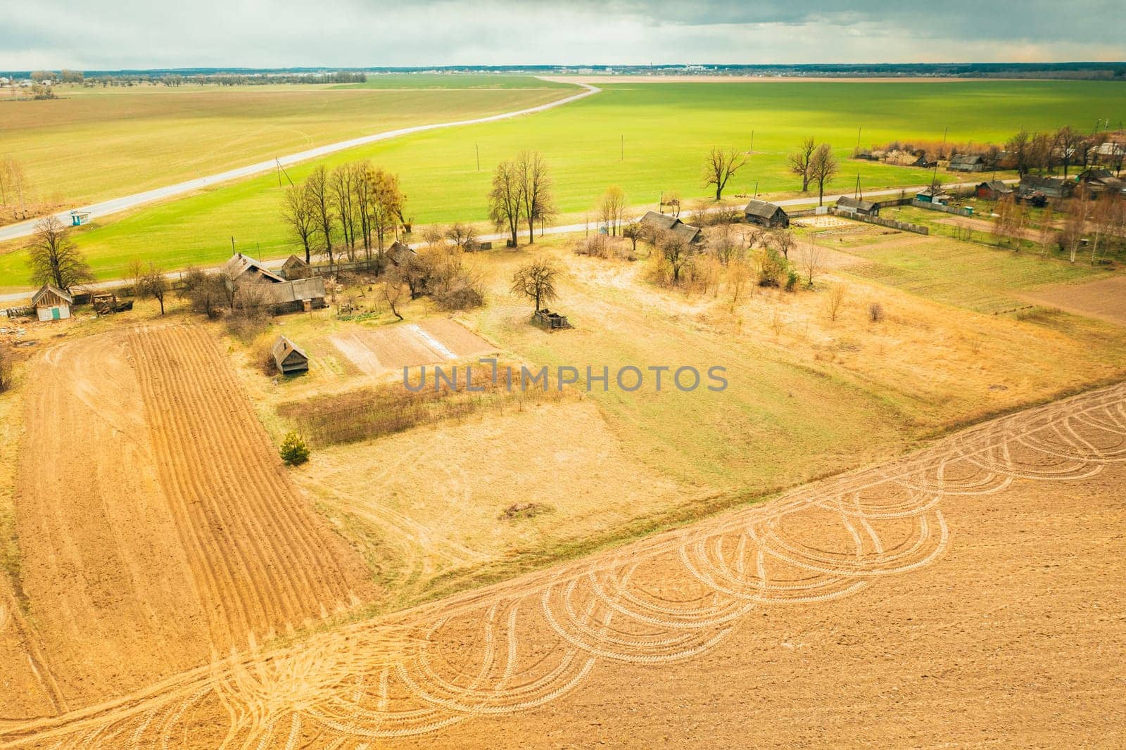 Belarus. Aerial View Of Belarusian Village. Beautiful Rural Landscape In Bird's-eye View. Beginning Of Agricultural Spring Season. Tracks On Plowed Field From Agricultural Machinery.