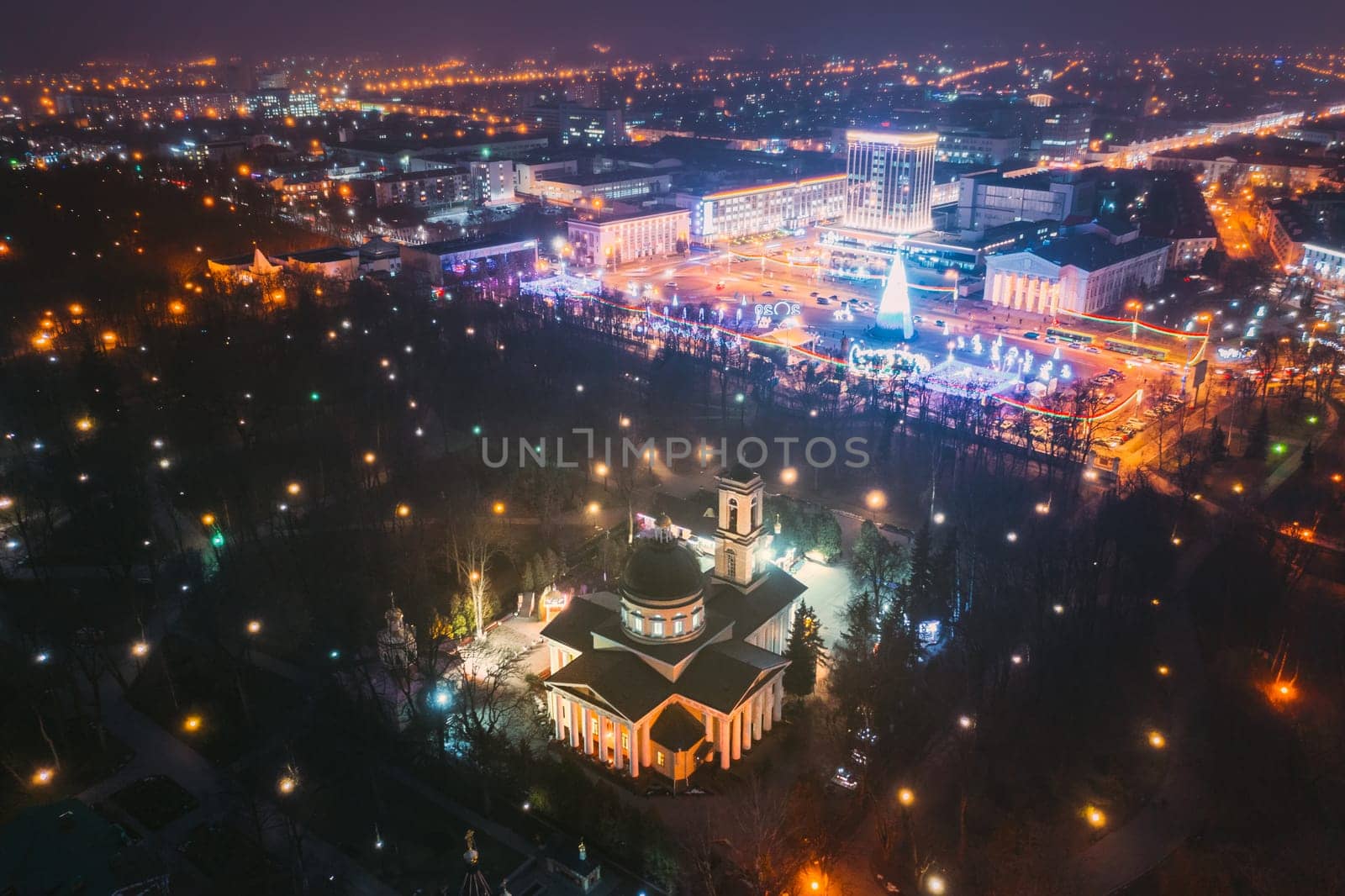 Gomel, Belarus. Main Christmas Tree And Festive Illumination On Square In Homel. New Year In Belarus. Aerial Night View. Peter And Paul Cathedral In Rumyantsevs And Paskeviches Park. Local Landmark.