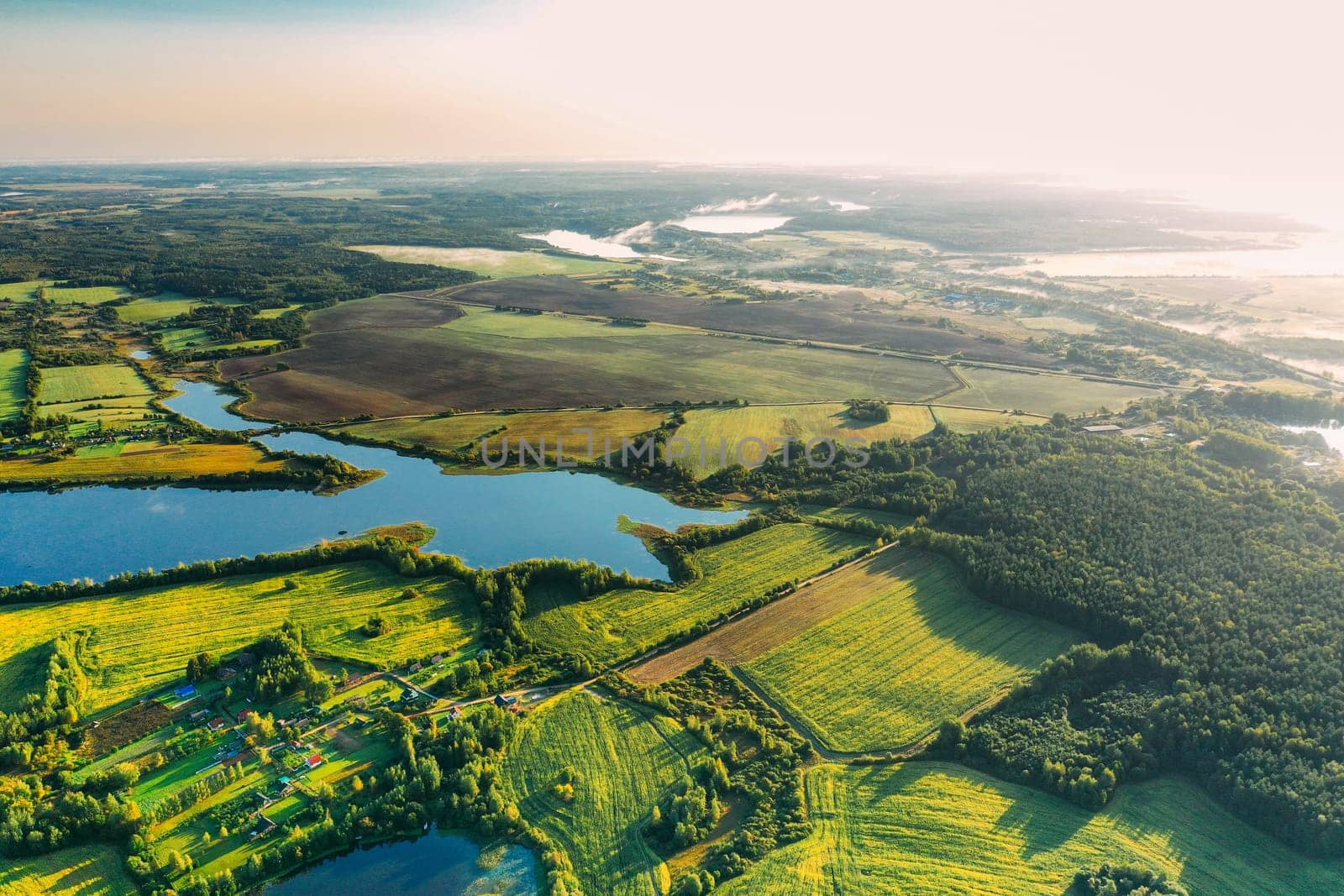 Lyepyel District, Vitebsk Region, Belarus. Aerial View Of Residential Area With Houses In Countryside. Morning Fog Above Lepel Lake. Sun Shining Above Town Skyline And Lepel Lake.