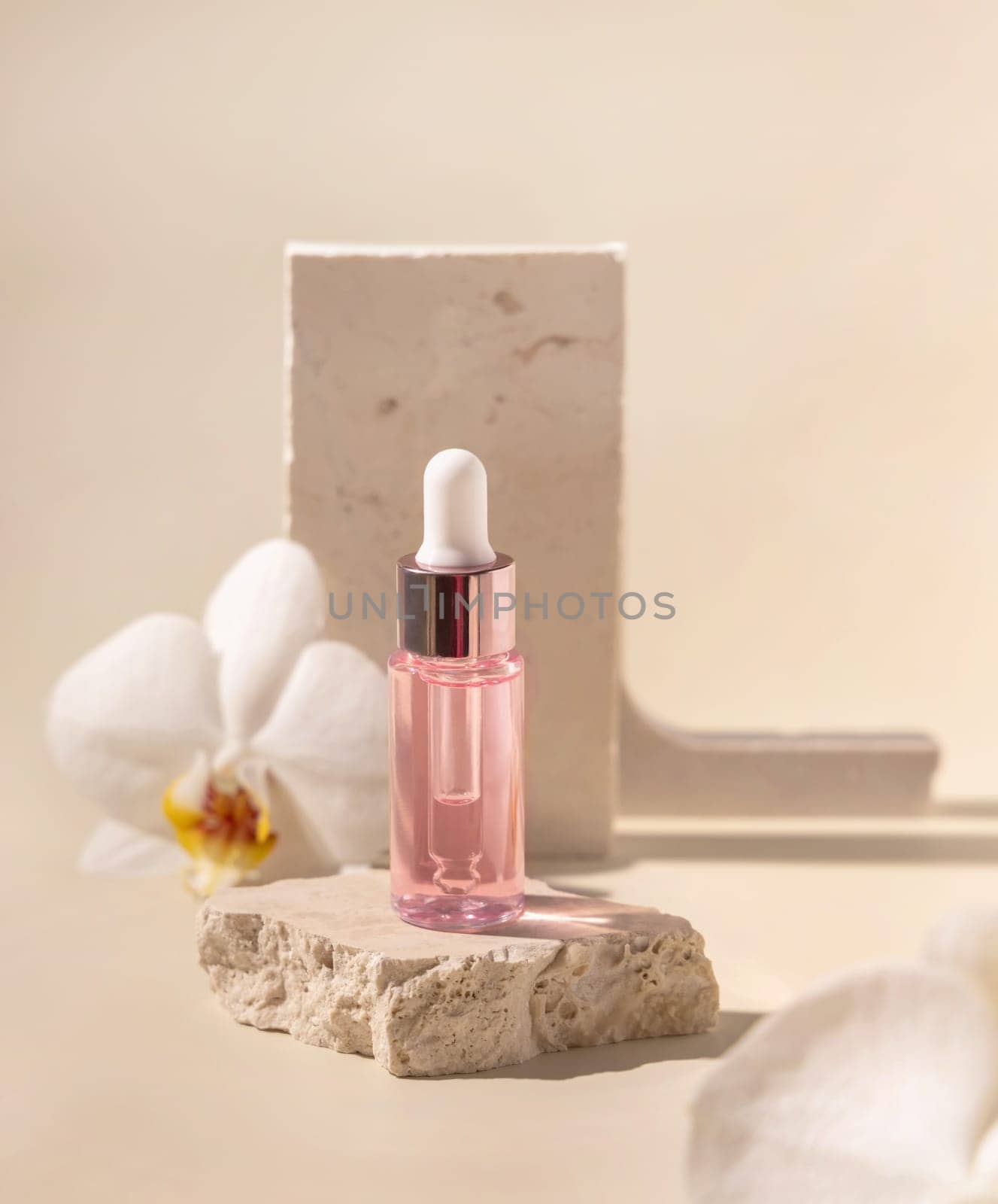 Dropper Bottle on stone near white orchid flowers on light yellow, close up, mockup. Skincare beauty product, essential oil or serum. Exotic cosmetics, pastel minimal composition..