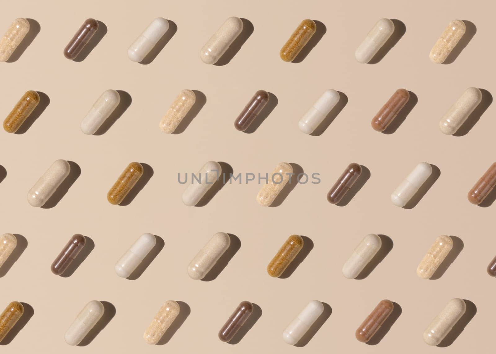 Capsules on light beige top view, hard shadows, creative pattern. Preventive medicine and healthcare, taking dietary supplements and vitamins. Assorted pharmaceutical medicine capsules