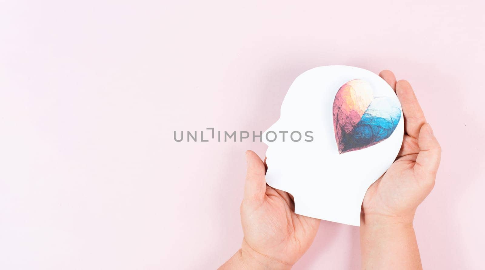 Holding a head with a colorful heart in the hands, symbol of love and positive emotion, charity and support