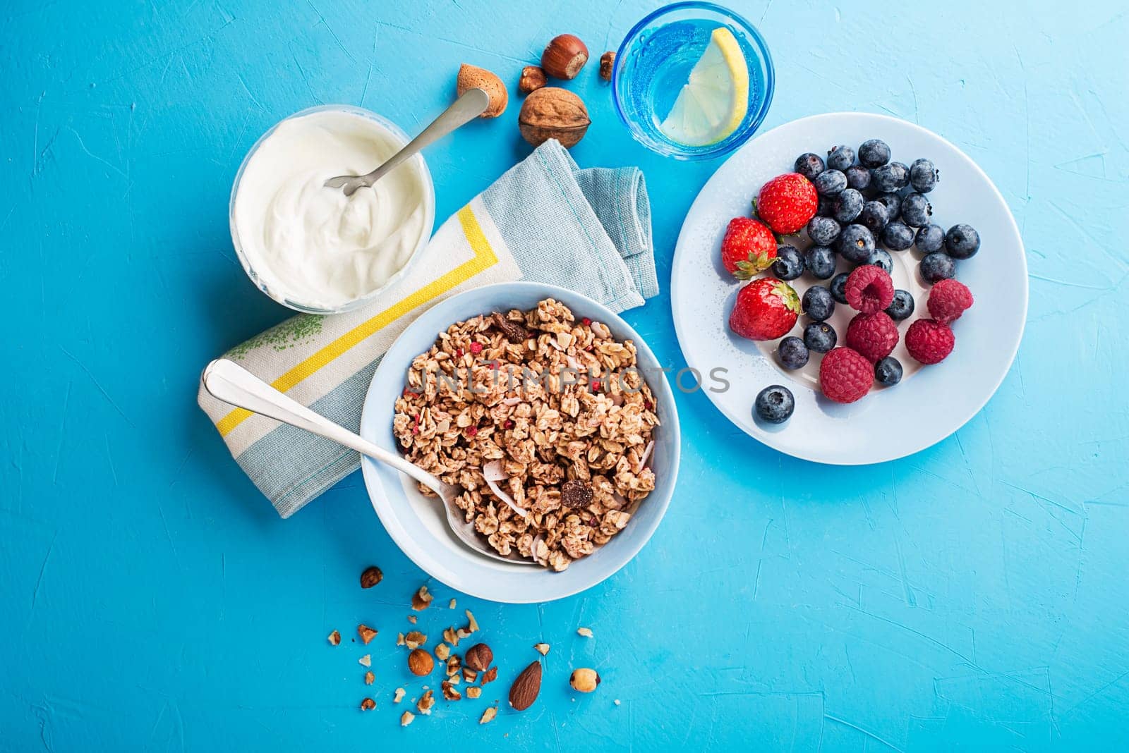 A plate of dry granola served with fresh berry fruit nuts and yogurt. Oatmeal plate. Healthy food, diet. Top view.