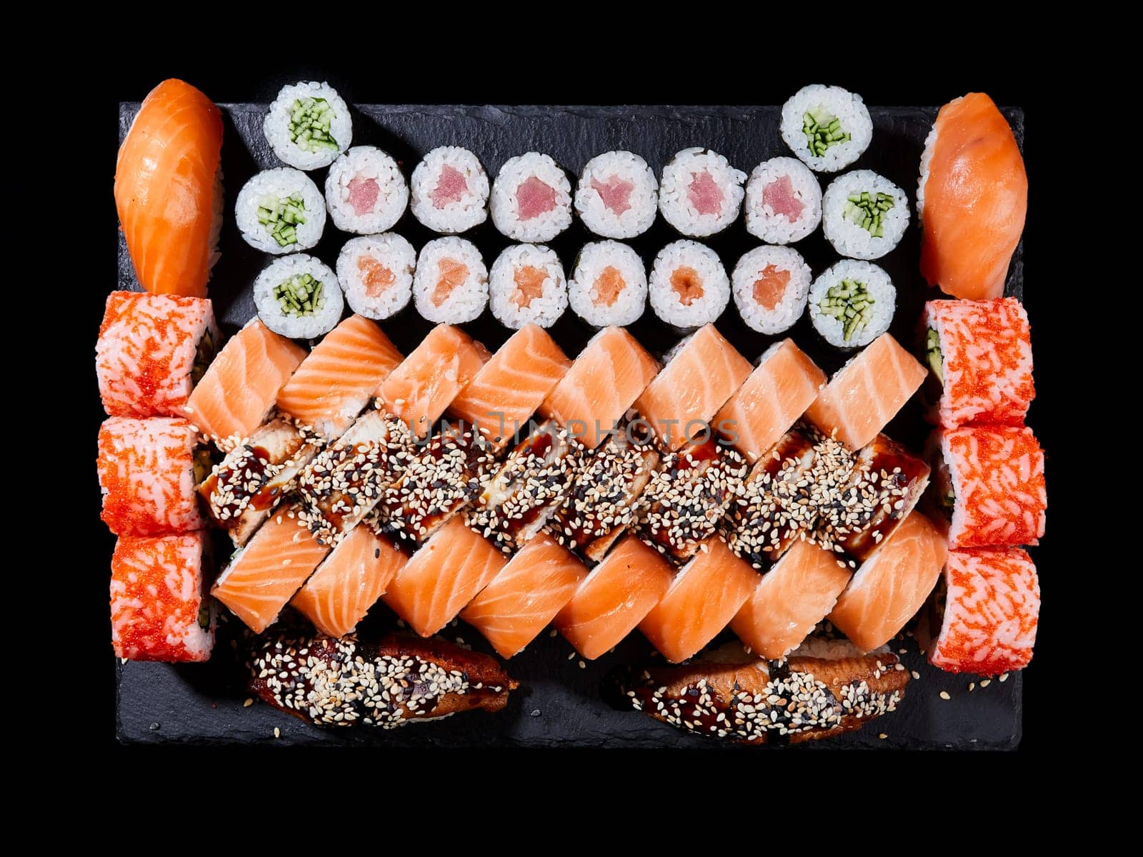 Japanese sushi food. Maki ands rolls with tuna, salmon, shrimp, crab and avocado are served on stone slate. Top view of assorted sushi. Rainbow sushi set, uramaki, hosomaki and nigiri.